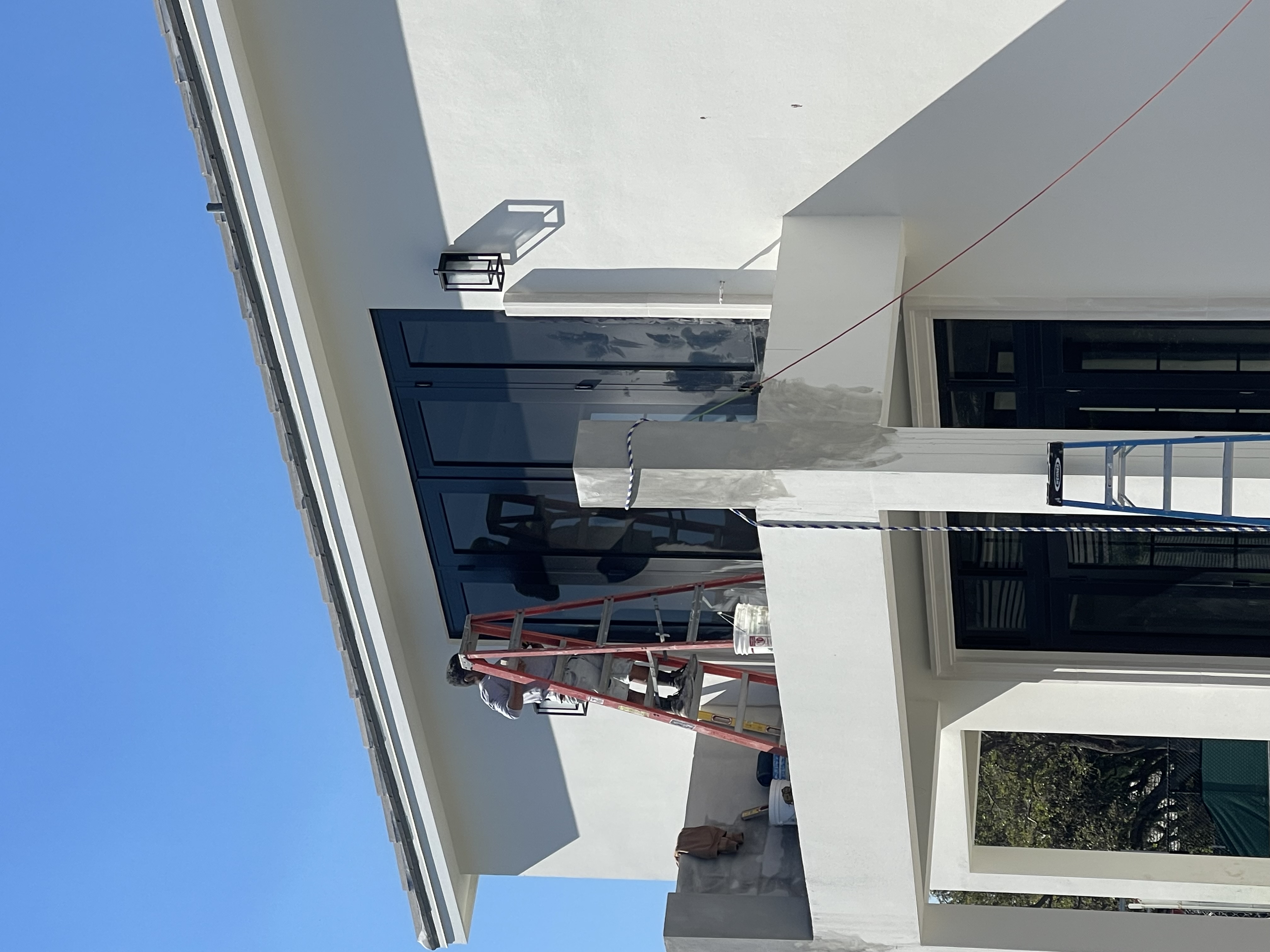 Painter on ladder finishing stucco exterior in Port St. Lucie Florida